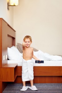 happy kid watching tv in hotel room after bathing